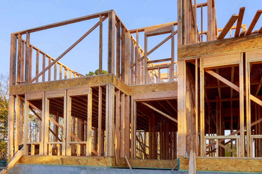 New house under construction framing against a blue sky New house under construction framing against a blue sky