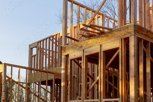 Close-up of beam built home under construction and blue sky with wooden truss, post and beam framework. Timber frame house, real estate background