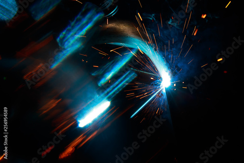 Arc welding. Welding of two metal plates in inert gases. MIG / MAG. A bright flash of light and a sheaf of sparks.