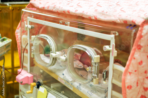 Sick newborn baby sleeping in a baby incubator in a hospital.