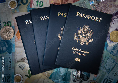 Four USA Passports with a backdrop of foreign currency meant to illustrate international exotic family travel around the world.