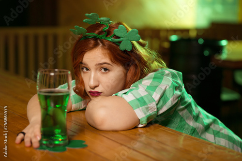 Red-haired pretty girl with shamrock headwear looking serious photo