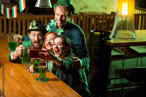 Company of good friends in st.patricks day costumes making selfie
