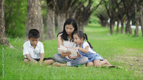 Asian families do activities together by reading books at the park happily.
