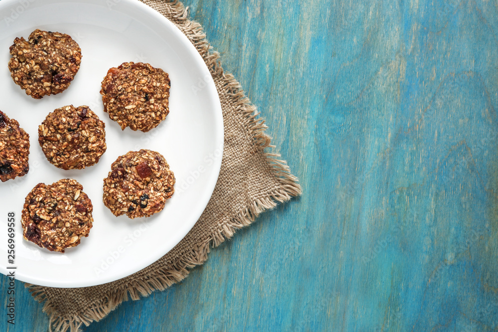 home made oat cookies with raisin on white plate on blue wooden background top view copy space . healthy food