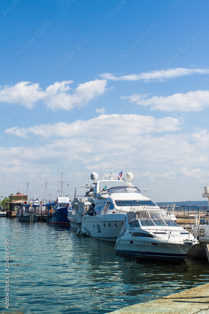 White yacht at the pier on the background of white clouds.