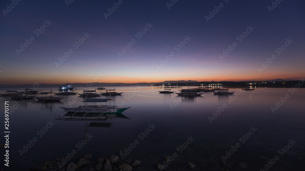 sunset at a bay of water and fishing port, the calm sea in low tide, a tranquil scene in a summer evening vacation mood 