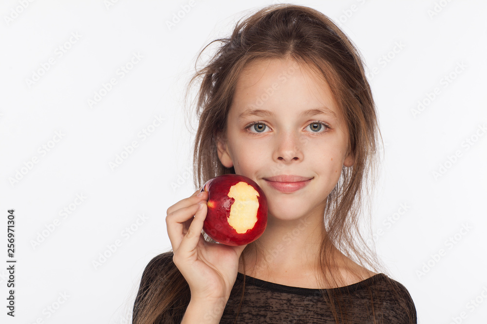 Beautiful emotional eight-year-old girl with an apple. Photo session in the studio. The girl is wearing a black blouse Beautiful emotional eight-year-old girl with an apple. Photo session in the studio. The girl is wearing a black blouse