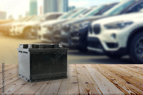 Photography Car battery on wooden table on blurred car park row on background