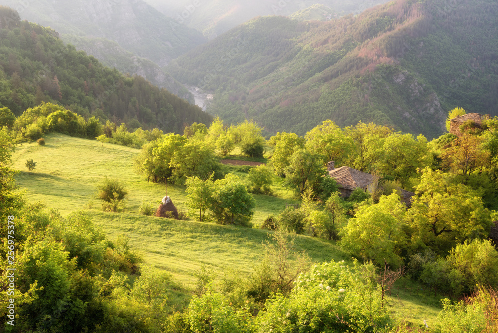 Spring is coming... Amazing spring view with a little village in Rhodopi Mountains, Bulgaria. Magnificent landscape, green fields, small houses.