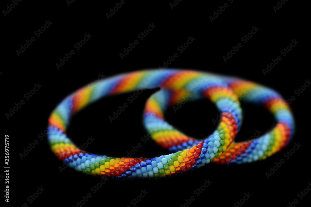 Set of rainbow mother-daughter bracelets isolated on a black background close up