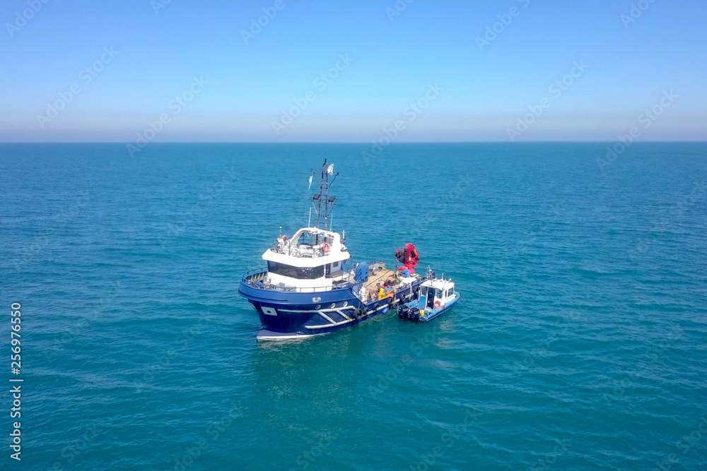 Fishing boat at sea with a smaller boat tied next to it - Aerial image.