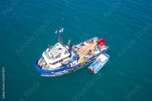 Fishing boat at sea with a smaller boat tied next to it - Aerial image. © STOCKSTUDIO