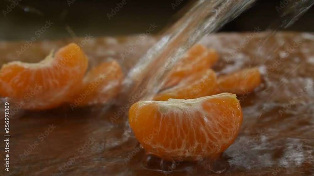 water splashing to piece of tangerine orange on wooden chop block water splashing to piece of tangerine orange on wooden chop block
