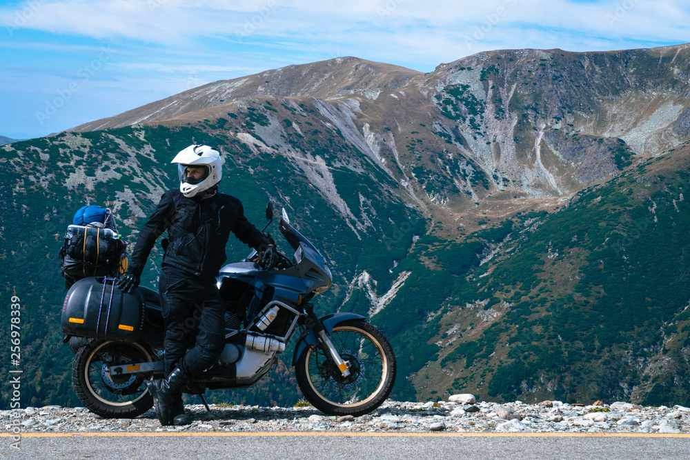 Motorcyclist man and Adventure Motorbike on the top of the mountain. Motorcycle trip. World Traveling, Lifestyle Travel vacations sport outdoor concept, copy space. Transalpina Romania
