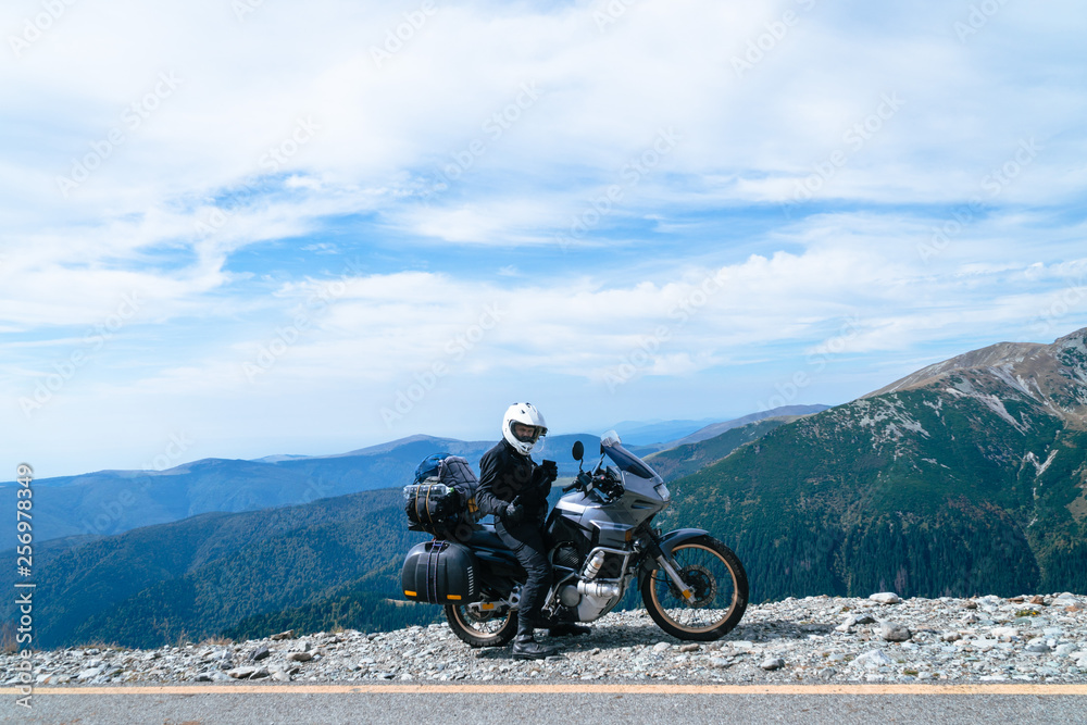 Obraz premium Motorcyclist man and Adventure Motorbike on the top of the mountain. Motorcycle trip. World Traveling, Lifestyle Travel vacations sport outdoor concept, copy space. Transalpina Romania