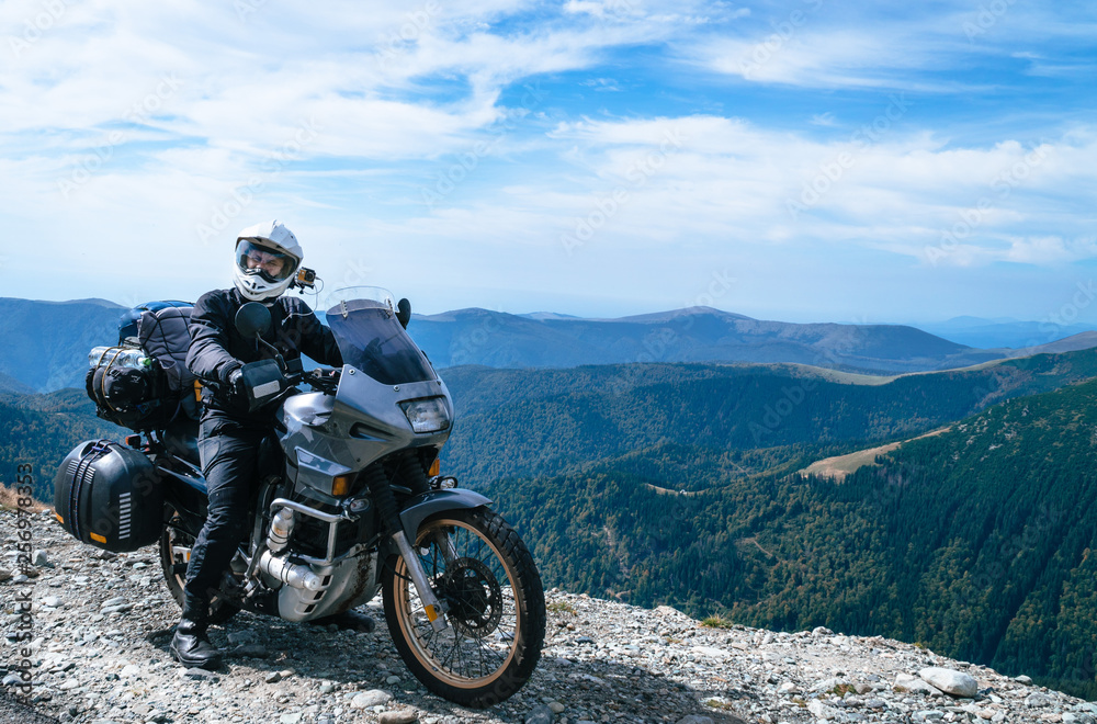 Motorcyclist man and Adventure Motorbike on the top of the mountain. Motorcycle trip. World Traveling, Lifestyle Travel vacations sport outdoor concept, copy space. Transalpine Romania Motorcyclist man and Adventure Motorbike on the top of the mountain. Motorcycle trip. World Traveling, Lifestyle Travel vacations sport outdoor concept, copy space. Transalpine Romania