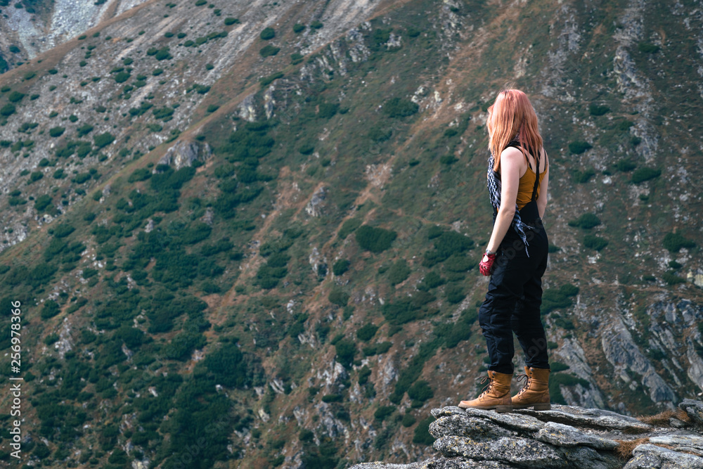 Obraz premium Winner. Success concept. Hiker girl in motorcycle pants after hiking to mountain top. copy spase. adventure Transalpina Romania
