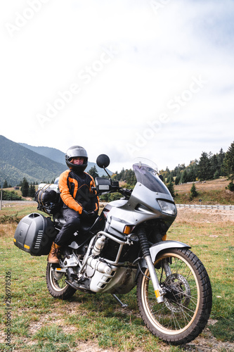 Woman biker with big adventure motorbike, motorcyclists vacation, world traveler, long road trip on two wheels. autumn day. Mountains on background. Romania