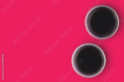 Pair of full glasses of aerated cola with bubbles on red table in cuisine. Copy space for your text. Top view. Rest concept
