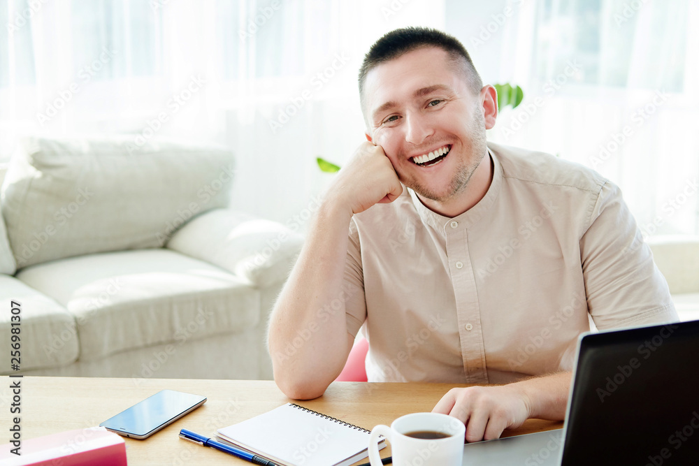 Portrait of happy smiling businessman sitting at wood desk with notepat and laptop computer in modern office and looking at camera, copy space Portrait of happy smiling businessman sitting at wood desk with notepat and laptop computer in modern office and looking at camera, copy space