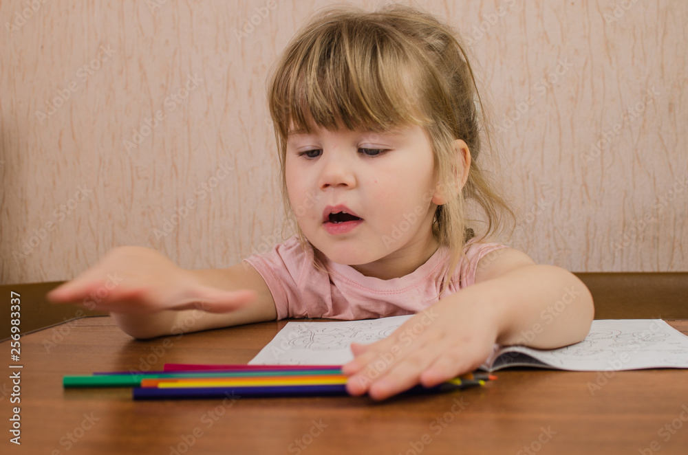 Cute little girl paints and tinkers with colored pencils and scissors Cute little girl paints and tinkers with colored pencils and scissors