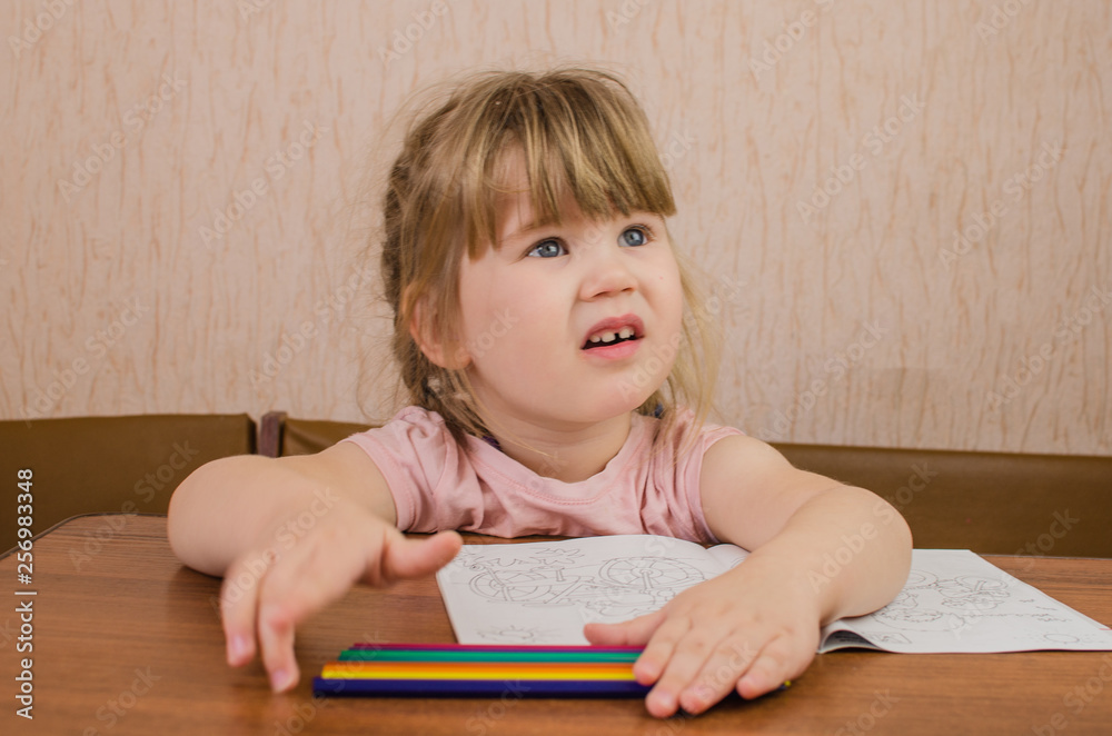 Cute little girl paints and tinkers with colored pencils and scissors Cute little girl paints and tinkers with colored pencils and scissors