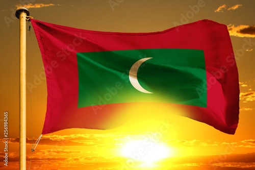 Maldives flag weaving on the beautiful orange sunset with clouds background