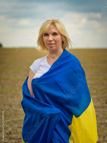 Young amazing beautiful girl with a huge Ukrainian flag on the field. Ukraine's Independence Day. © leo_nik