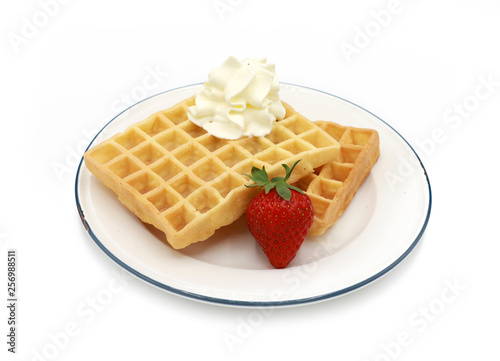 fresh belgian waffles with strawberries and whipped cream on a plate isolated on white background