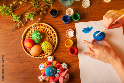 The hands of the artist paint Easter eggs. Watercolor paints in cans and tubes. Handwork.