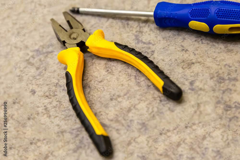 pliers screwdriver screwdriver with blue handle focus bottom of frame close-up tool manual help to master