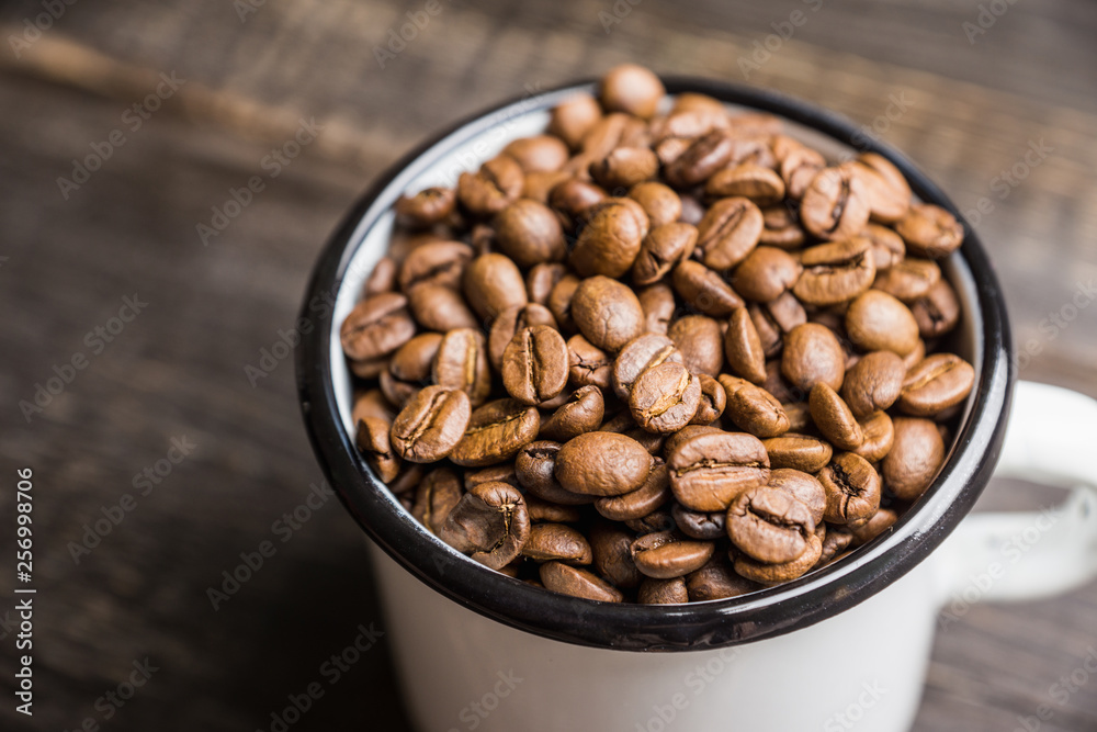 Metal cup full of coffee beans. Selective focus. Shallow depth of field.