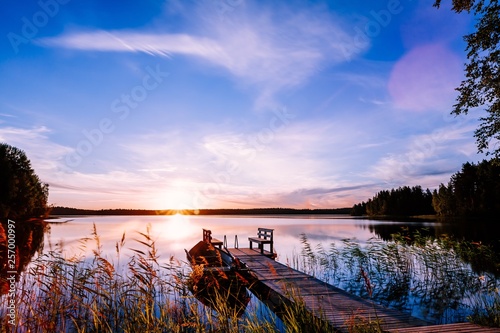 Fototapeta Naklejka Na Ścianę i Meble -  Wooden pier with fishing boat at sunset on a lake in Finland