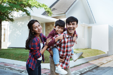 asian family standing in front of their new house together. mother father and son new home
