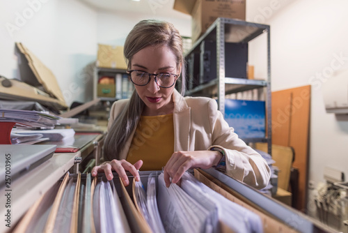 wide angle of attractive office woman working looking files in basement