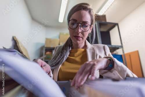 wide angle of attractive office woman working looking files in basement