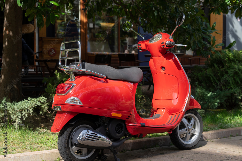 A vintage red scooter in the street.