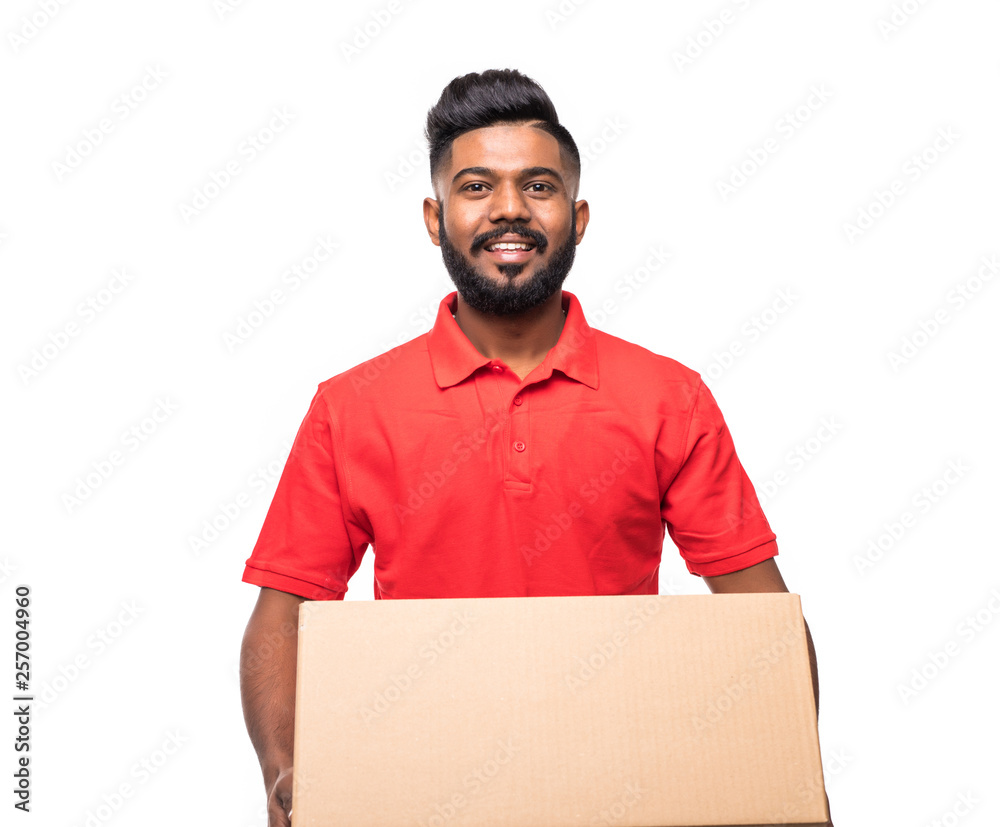 Young smiling indian logistic delivery man in red uniform holding the box on white background Young smiling indian logistic delivery man in red uniform holding the box on white background