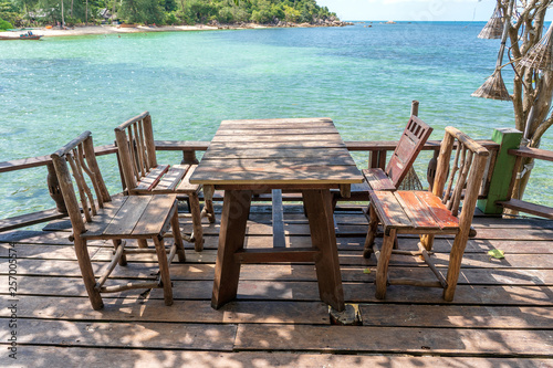 Wooden table and chairs in empty beach cafe next to sea water. Island Koh Phangan  Thailand