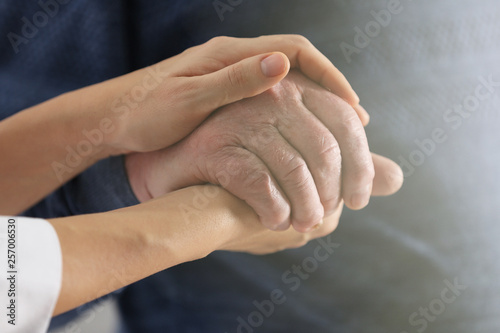 Volunteer holding hand of senior man, closeup