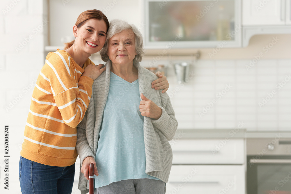 Elderly woman with female caregiver in kitchen. Space for text - obrazy, fototapety, plakaty 