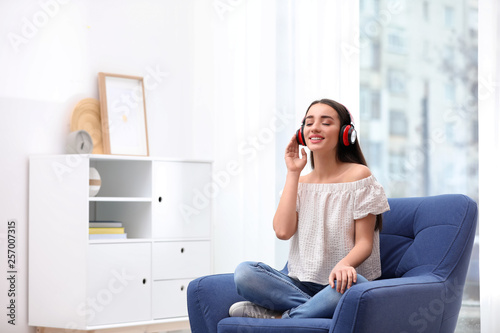 Young woman with headphones resting in armchair at home