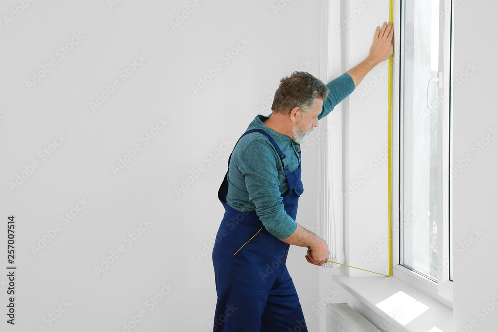 Service man measuring window for installation indoors. Space for text