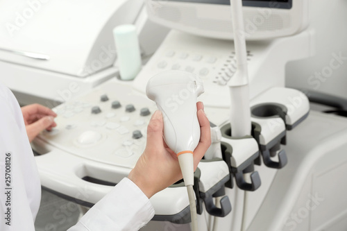 Professional sonographer using modern ultrasound machine in clinic, closeup photo