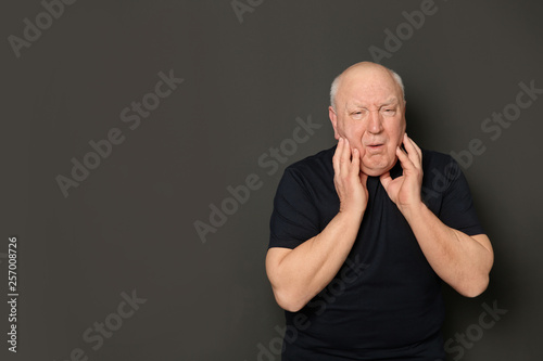 Senior man suffering from cough on dark background. Space for text