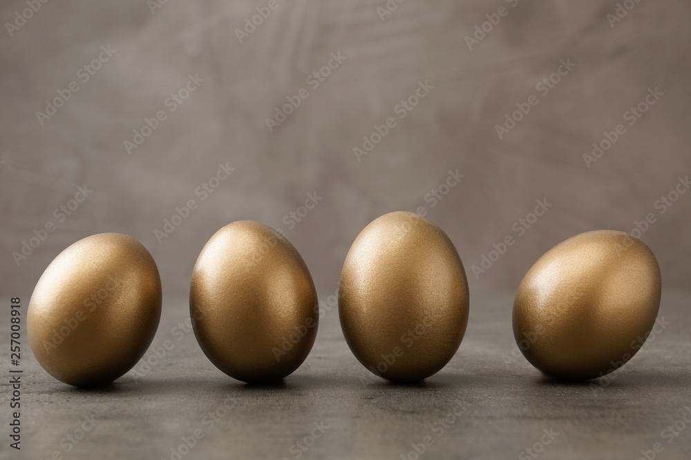 Many shiny golden eggs on grey table Many shiny golden eggs on grey table