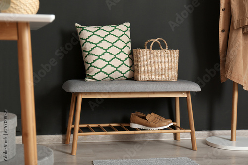 Bench with pillow and bag at black wall. Interior design