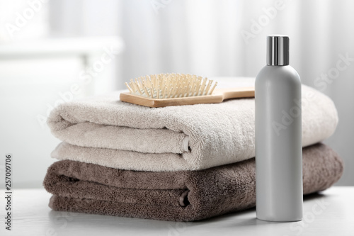 Towels with hair brush and shampoo on table