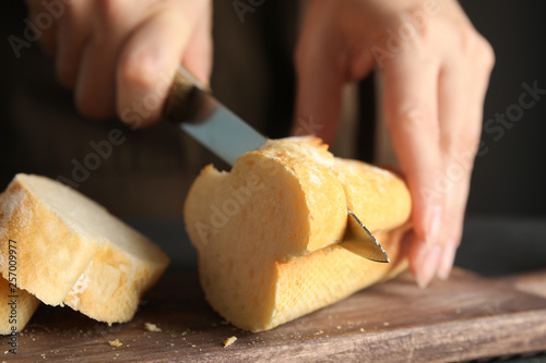 Woman cutting bread on wooden board, closeup
